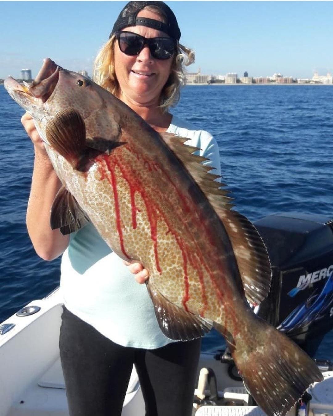 Angler holding a grouper caught bottom fishing off Palm Beach, Florida