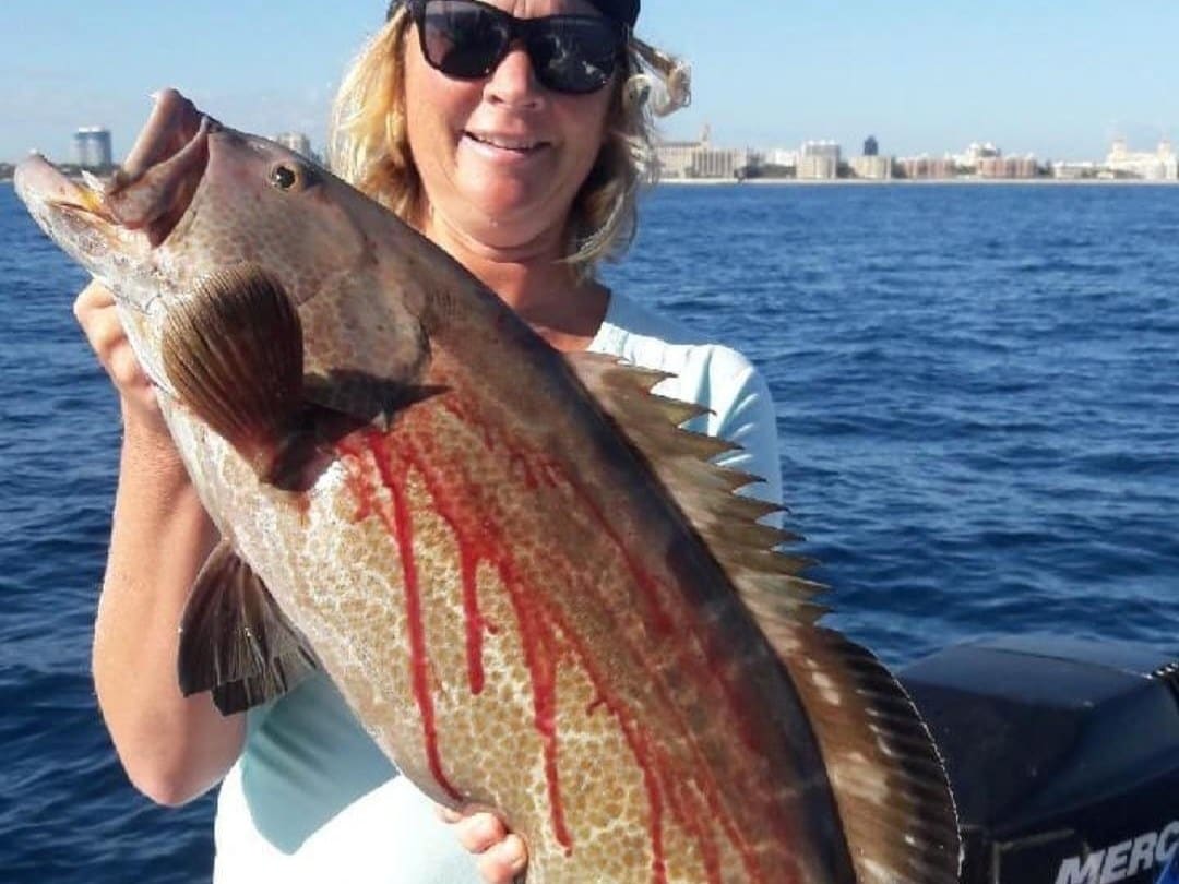 Angler holding a grouper caught bottom fishing off Palm Beach, Florida