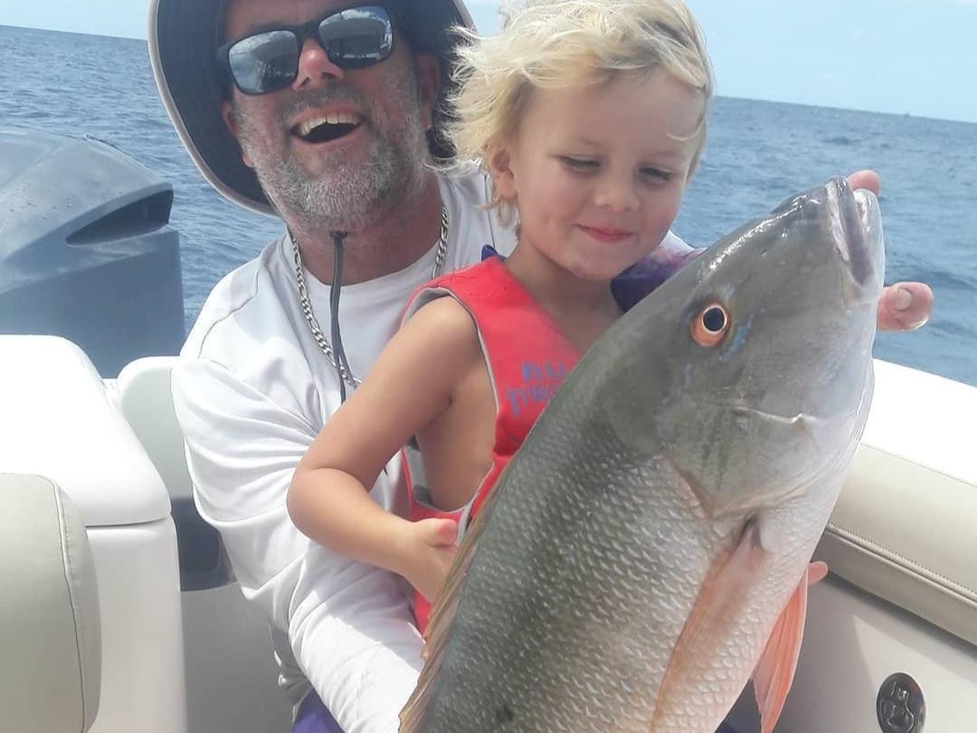 Father and young child holding a mutton snapper aboard a Lake Worth fishing charter