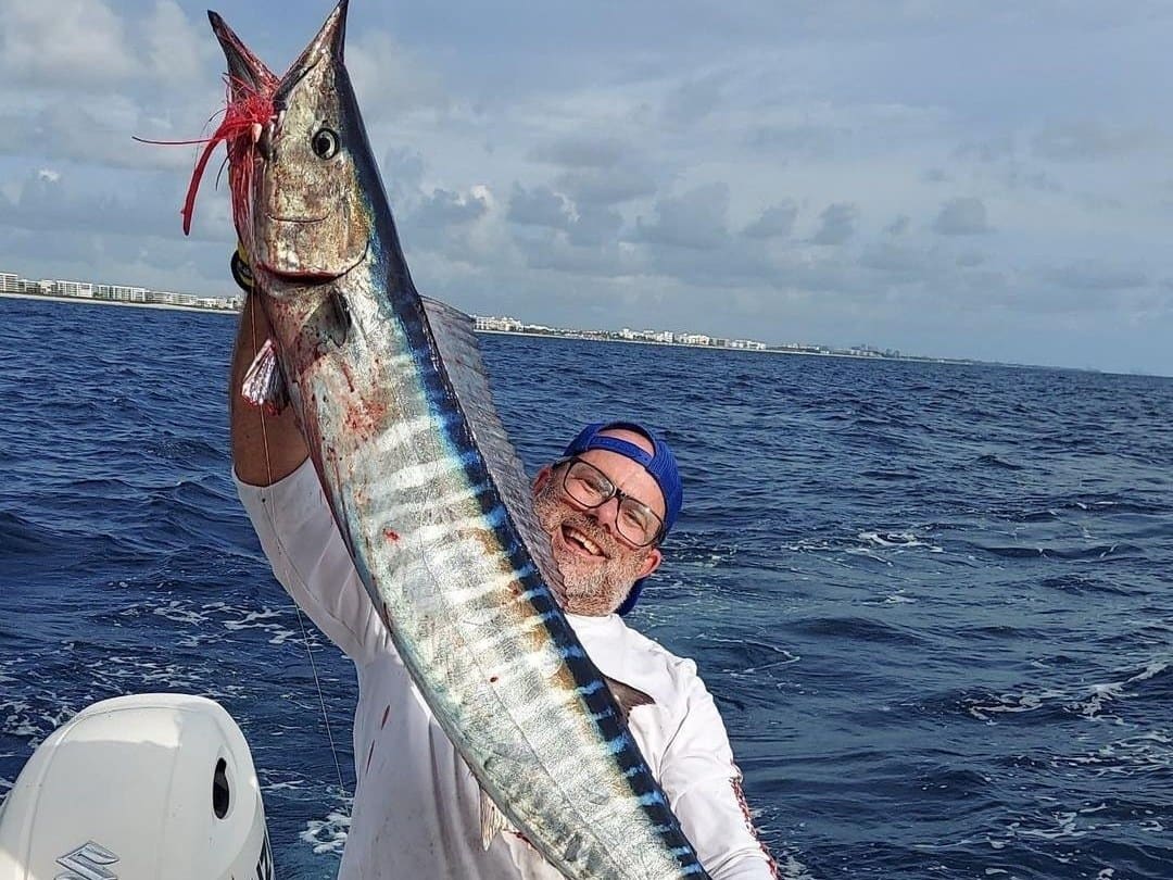 Angler lifting a wahoo caught in the Gulf Stream off Palm Beach County on a charter