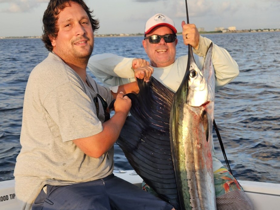 Two anglers with a sailfish landed on a Palm Beach sailfish charter