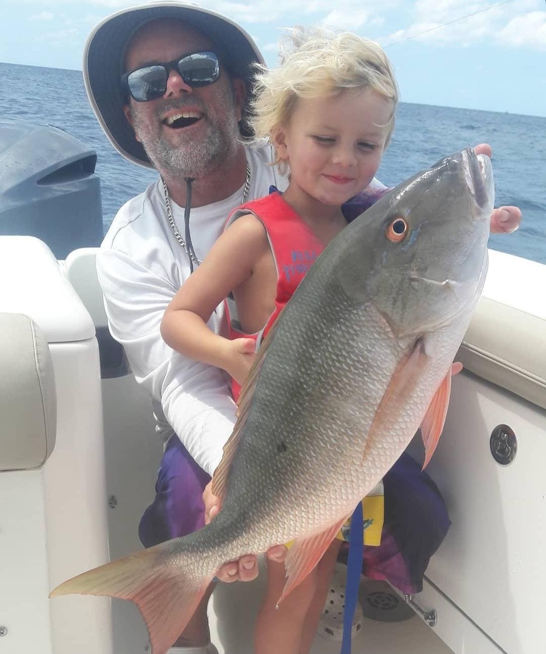 Father and young child holding a mutton snapper aboard a Lake Worth fishing charter