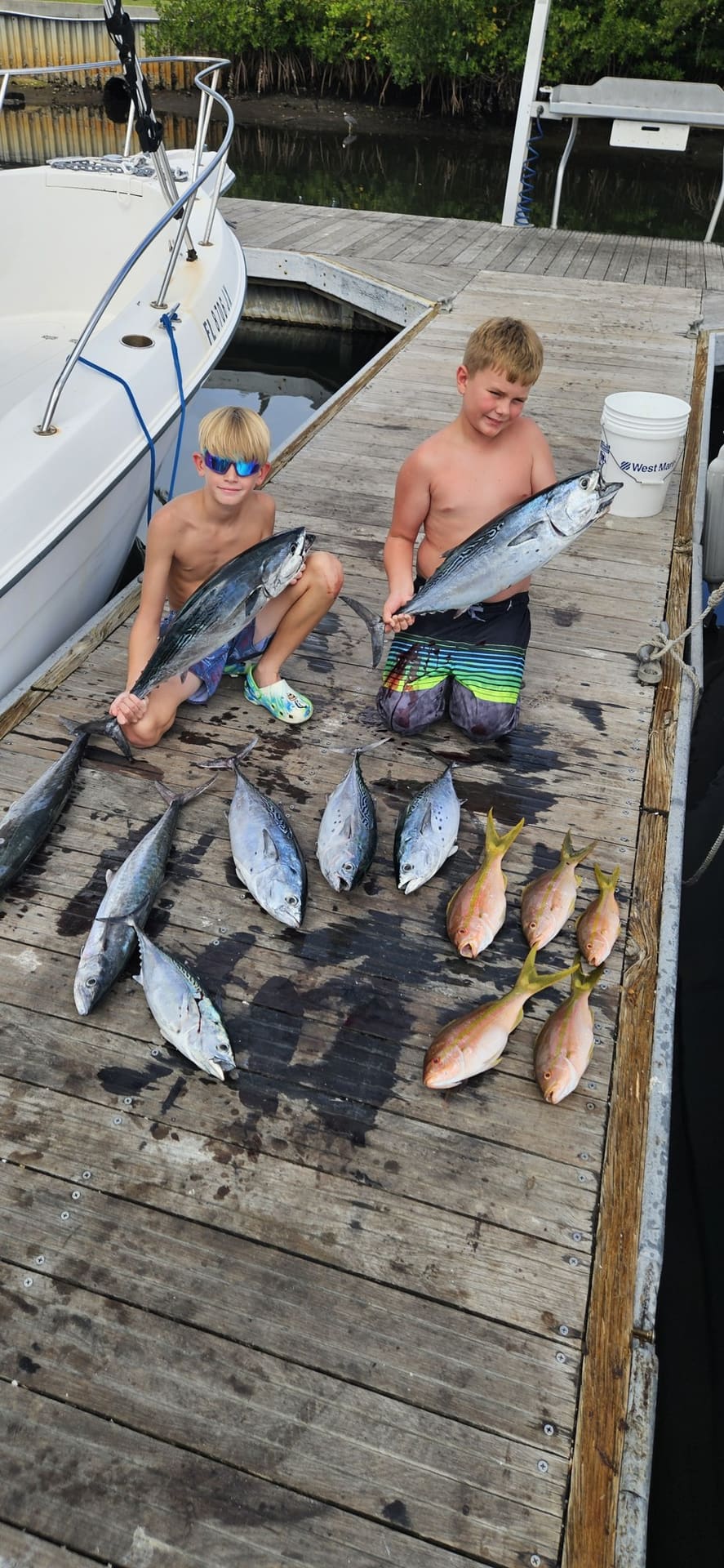 Two young anglers on the dock with a day's catch of snapper and tuna from a Lake Worth charter