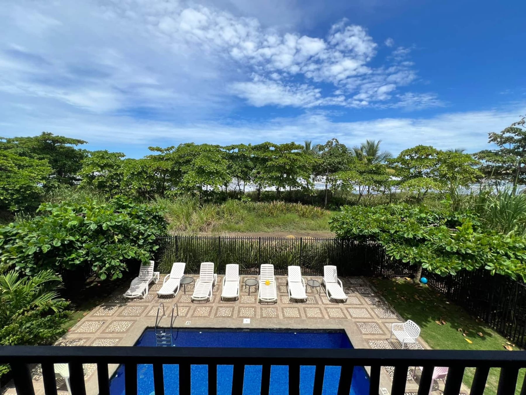 The pool deck seen from the villa's balcony, jungle beyond