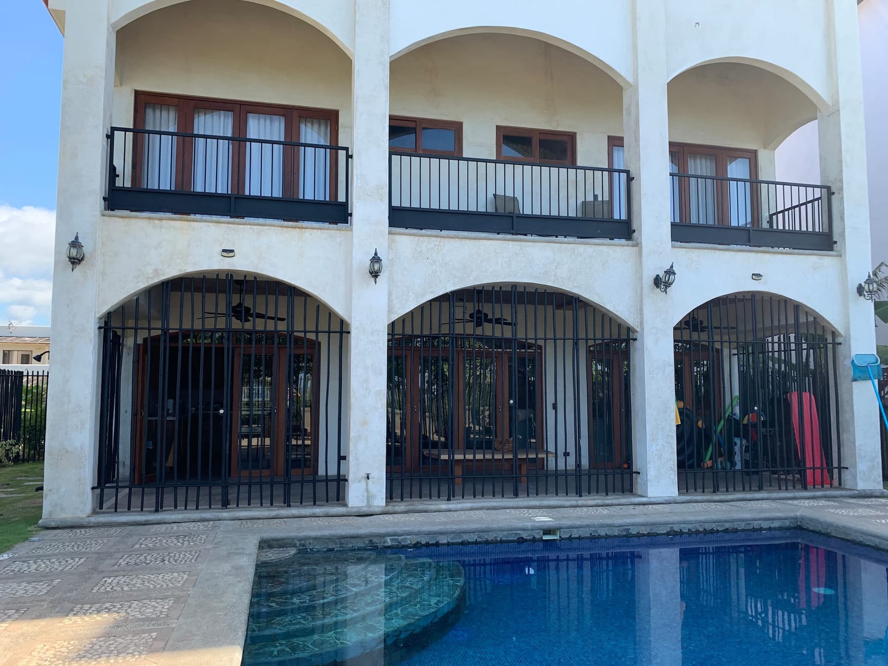 The villa's arched two-storey front and the pool