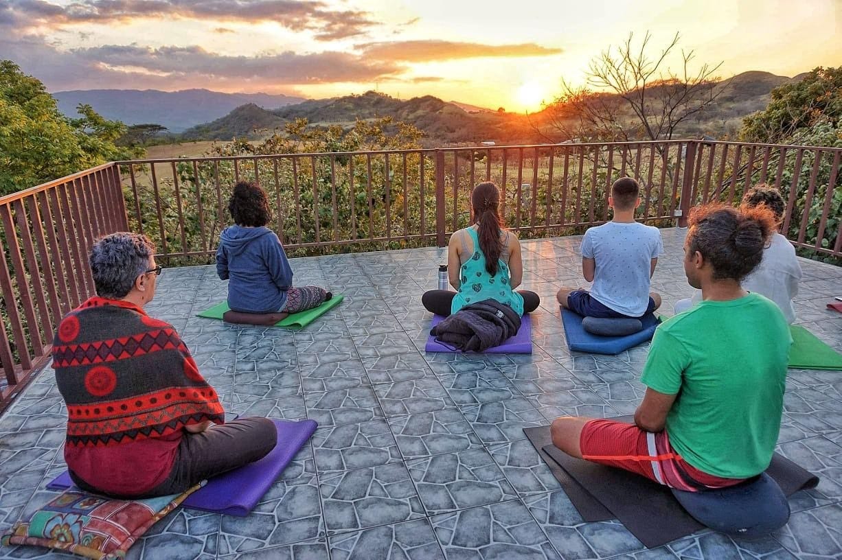 A group doing yoga on a deck above the Costa Rican hills at sunset