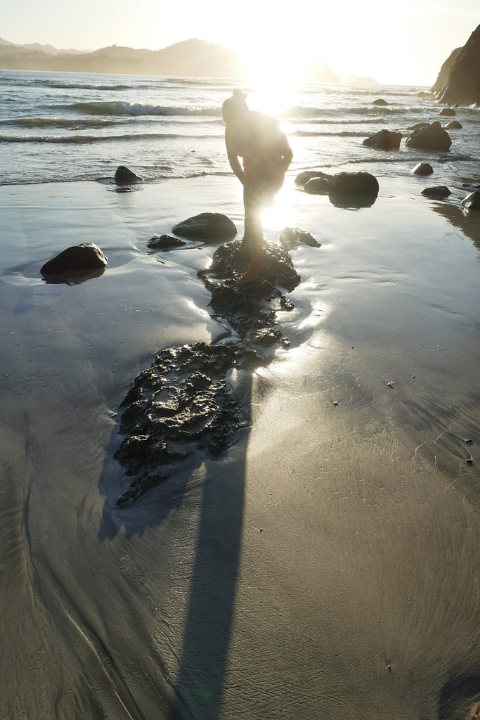 A woman practicing yoga at sunrise on Playa Sámara, Costa Rica, reflected in the wet sand