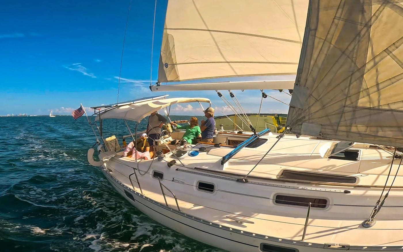 The Beneteau heeling under full sail with guests in the cockpit