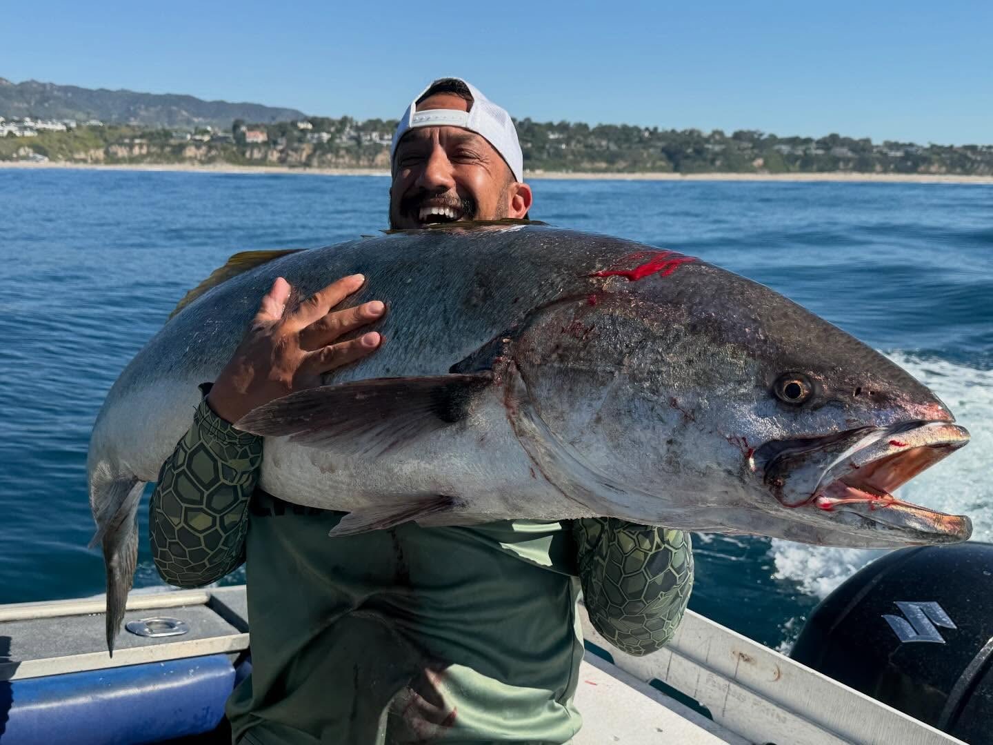An angler hugging a huge fish on the deck