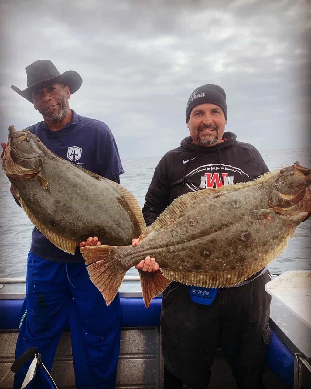 Two anglers each holding a halibut