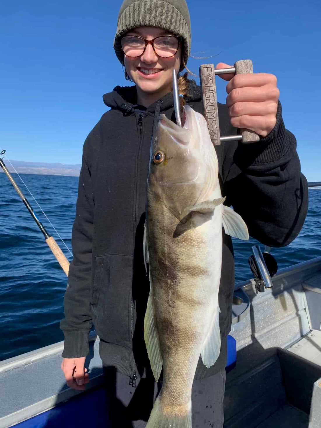 A young angler holding a lingcod