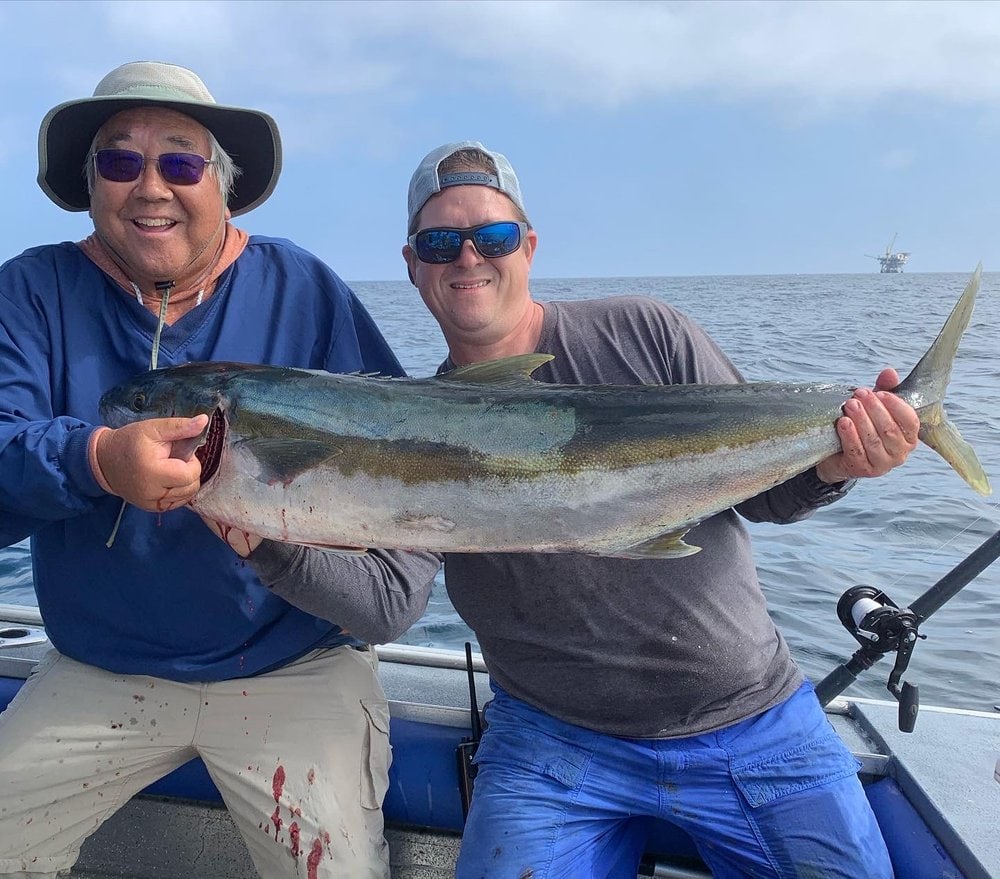 Two anglers holding a 32 lb yellowtail
