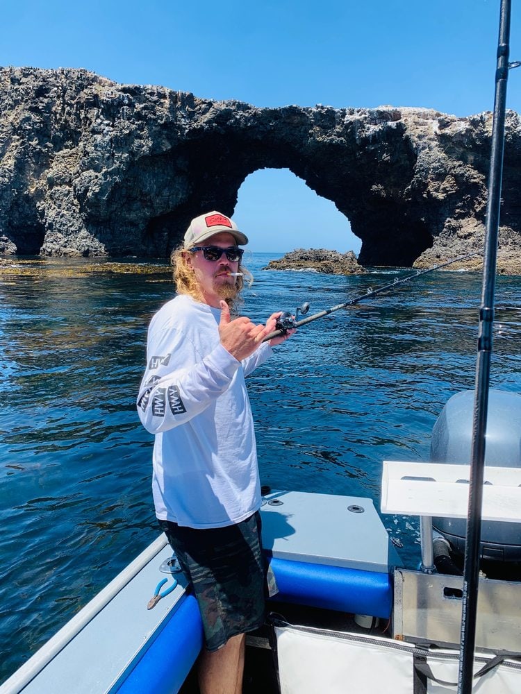 An angler on the deck with Anacapa's arch behind