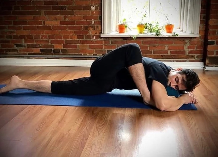 A reclined twist on a mat against the brick wall