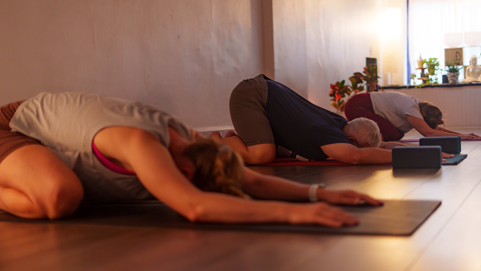 A full class resting in child’s pose across the Lakewood Yoga practice room