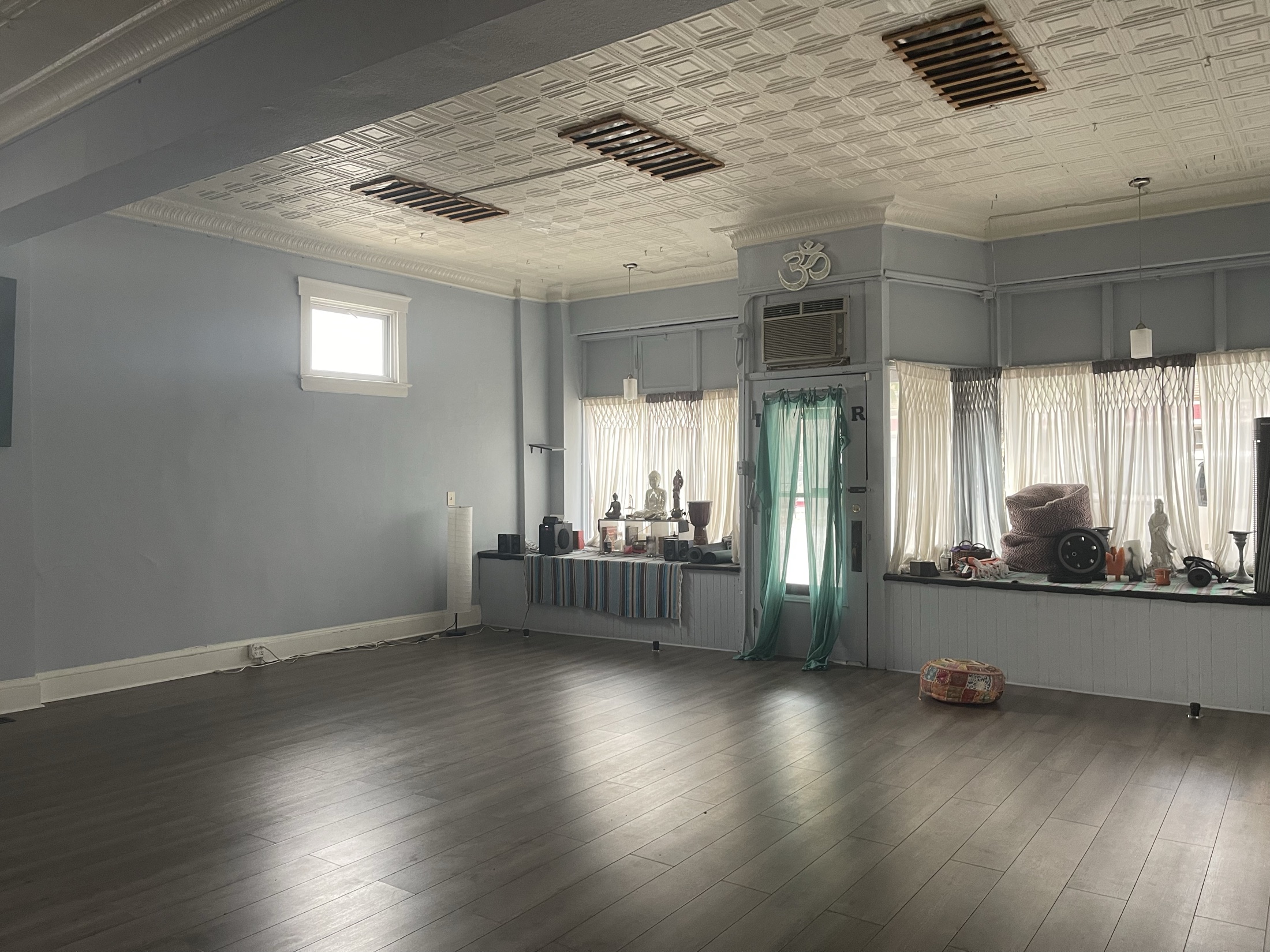 The Lakewood Yoga practice room: wood floor, pressed-tin ceiling, bay windows