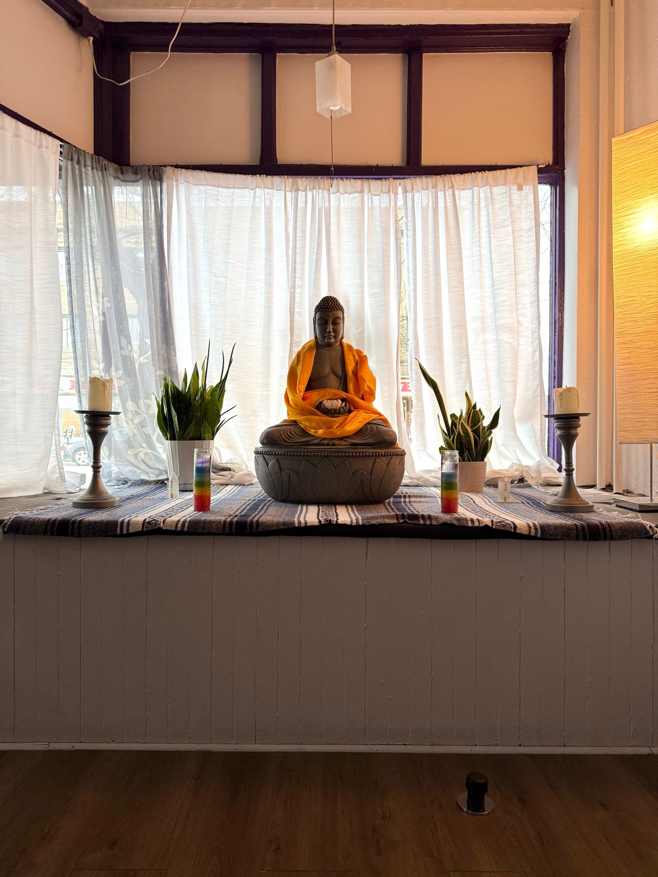 The altar in the bay window at Lakewood Yoga, lit by a warm lamp