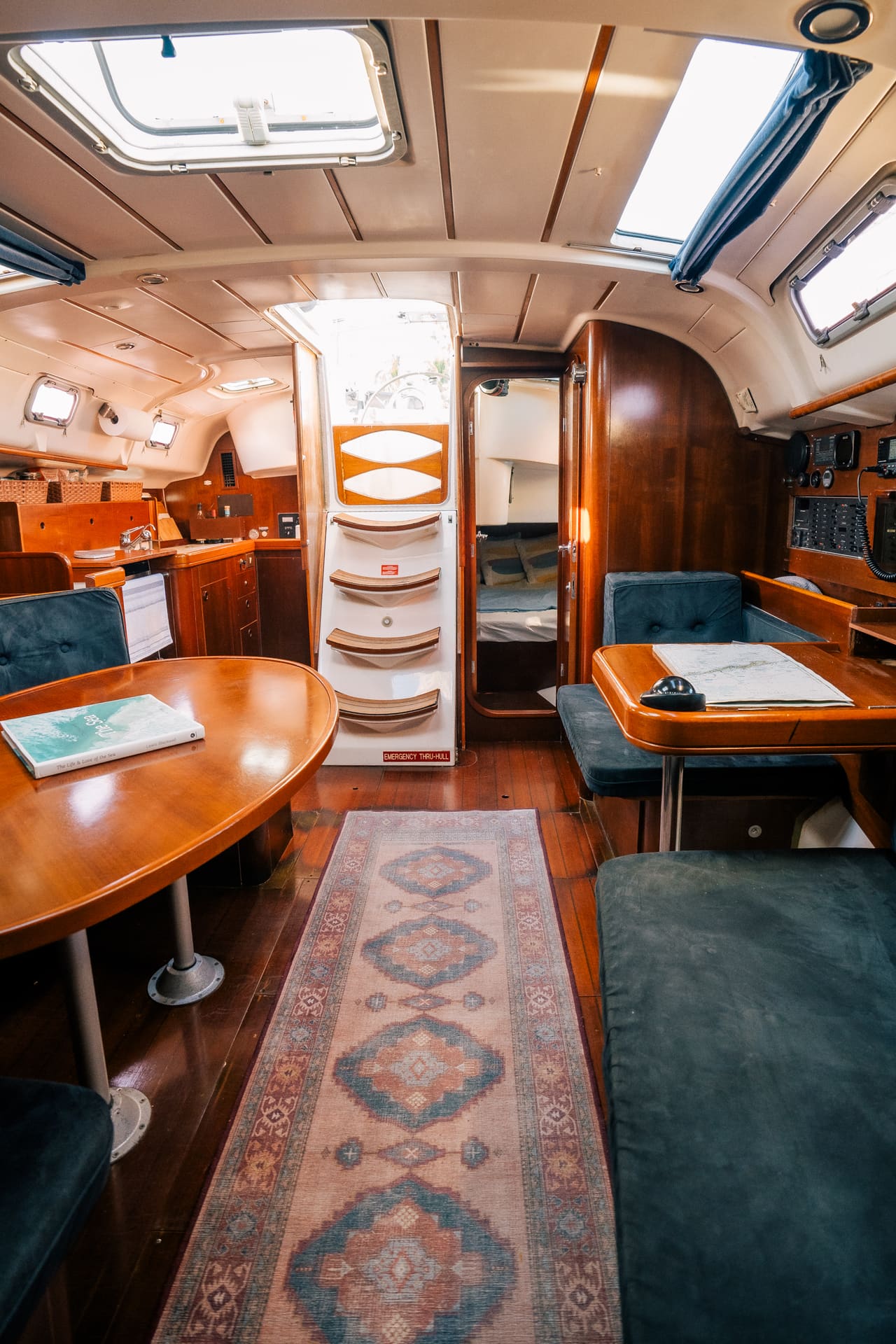 Cozy sailboat cabin interior with wood finishes, blue cushions, and nautical charts