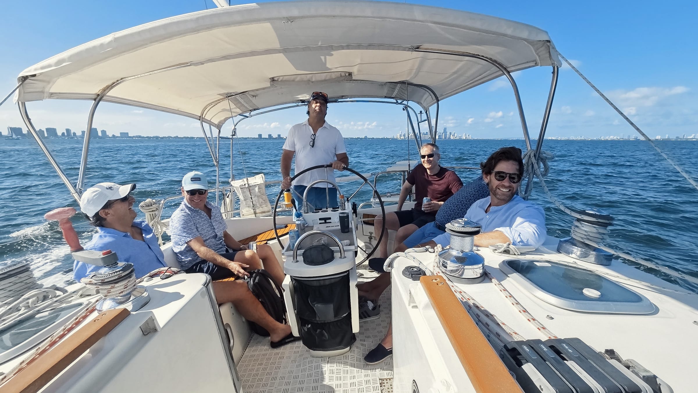 Five men relaxing on a sailing yacht on a sunny blue bay