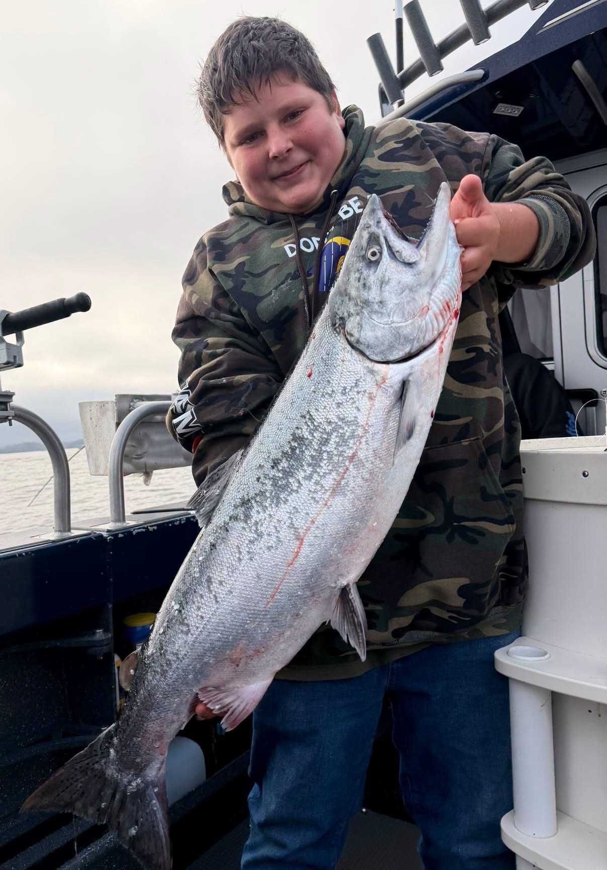 A boy holding a king salmon on the boat