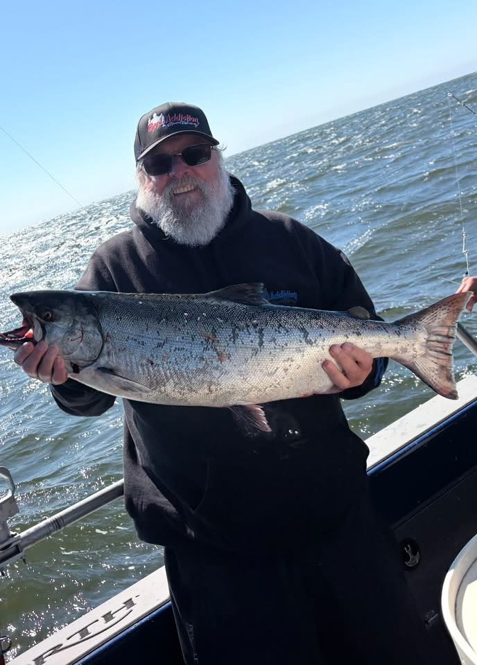 An angler holding a king salmon out on the ocean