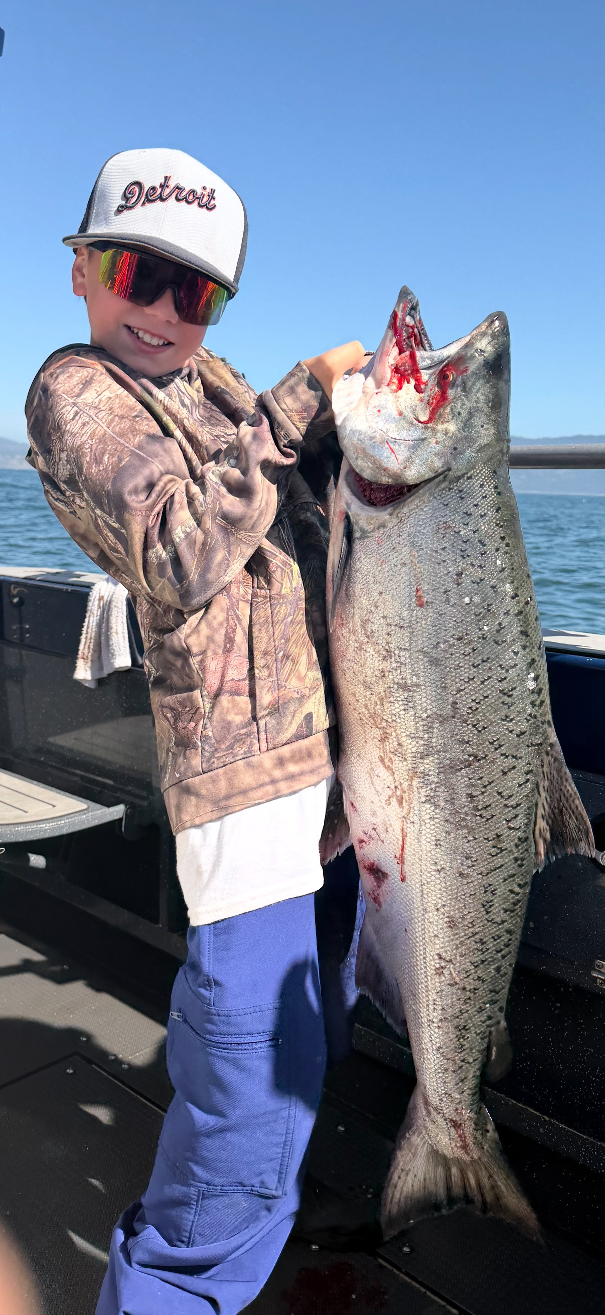 A young angler holding up a king salmon nearly as tall as he is