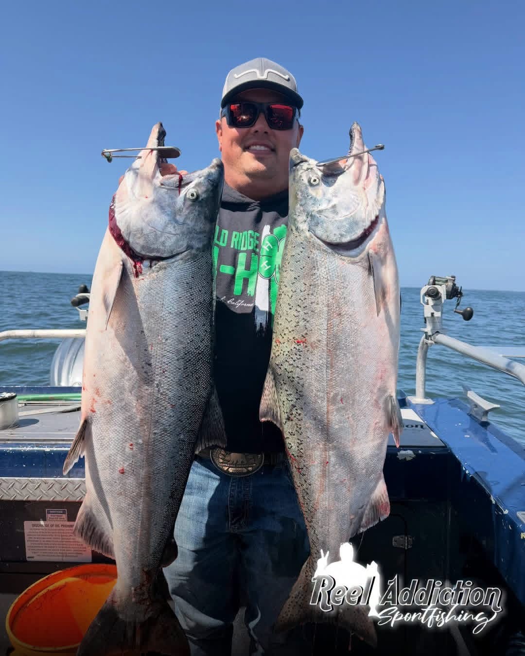 An angler holding two king salmon on the boat