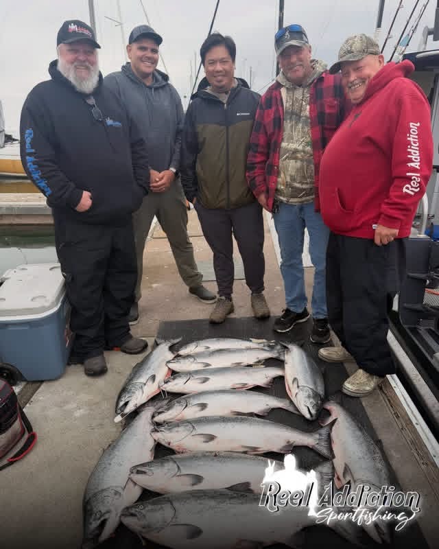 Five anglers on the dock behind a row of king salmon