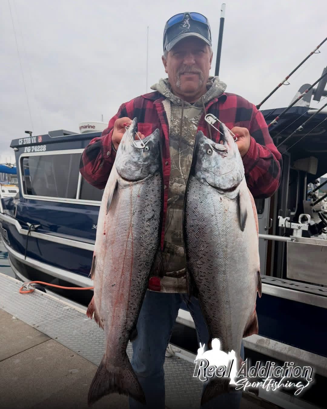 An angler on the dock holding two king salmon