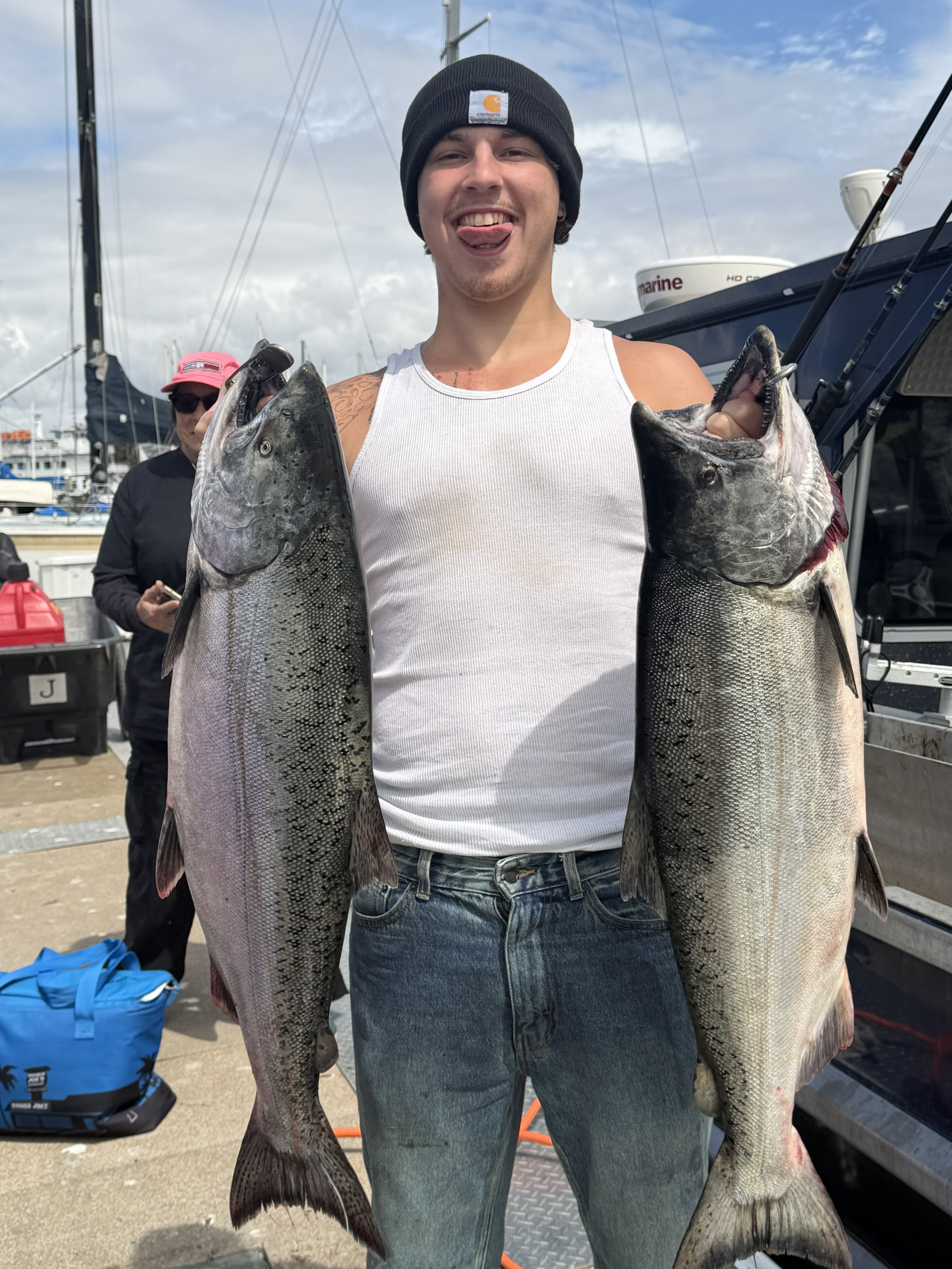 A young angler on the dock holding two king salmon