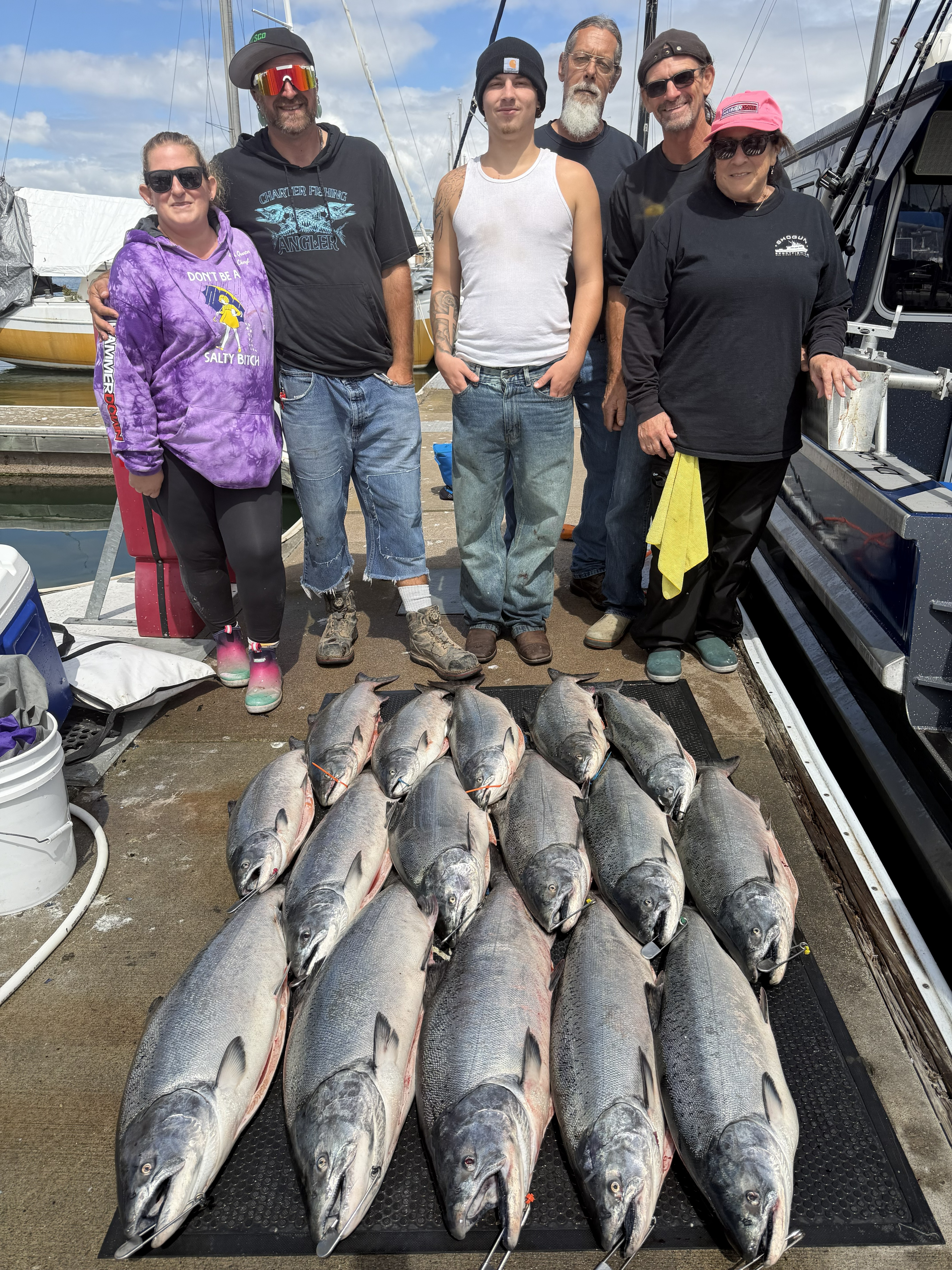 A family on the dock behind rows of king salmon