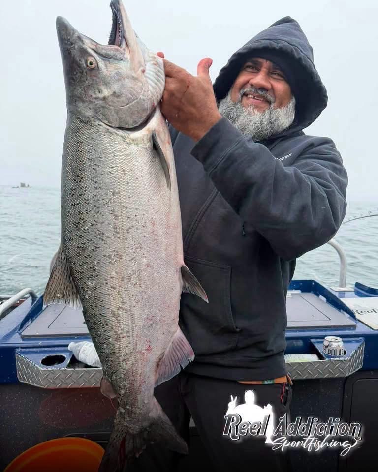 A smiling angler holding up a big king salmon