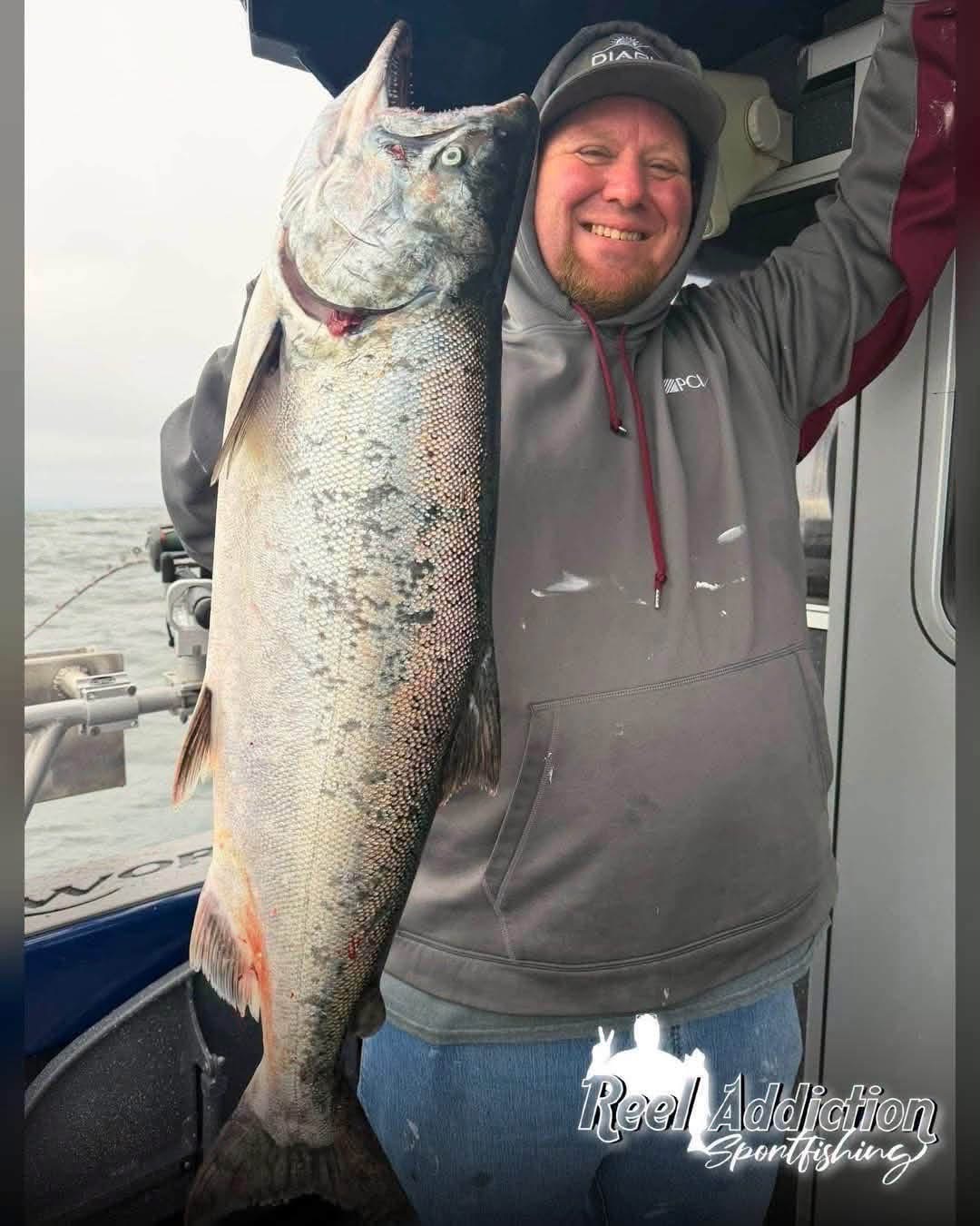 An angler holding a big king salmon in the cabin doorway