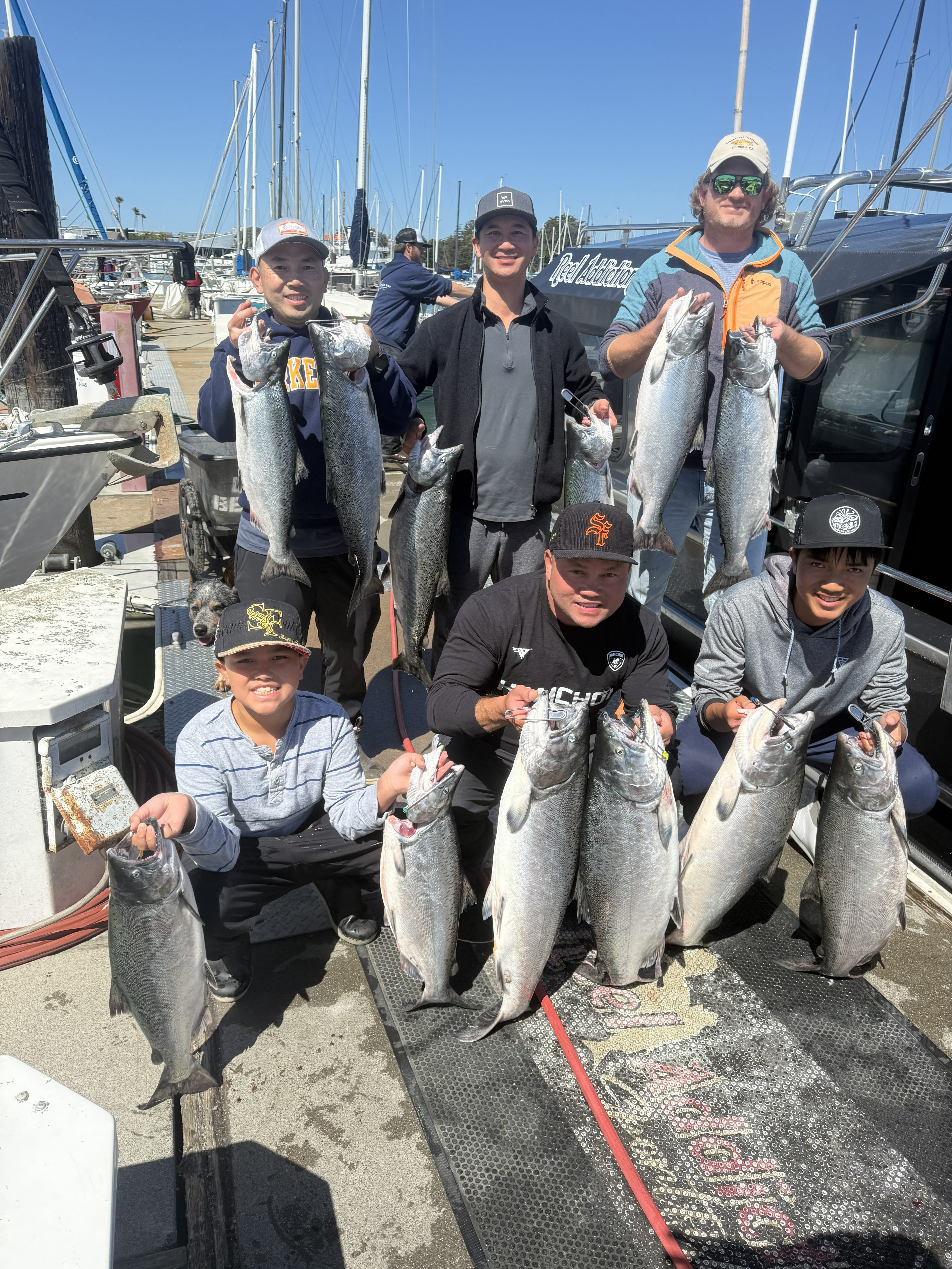 Eight anglers on the dock, each holding king salmon