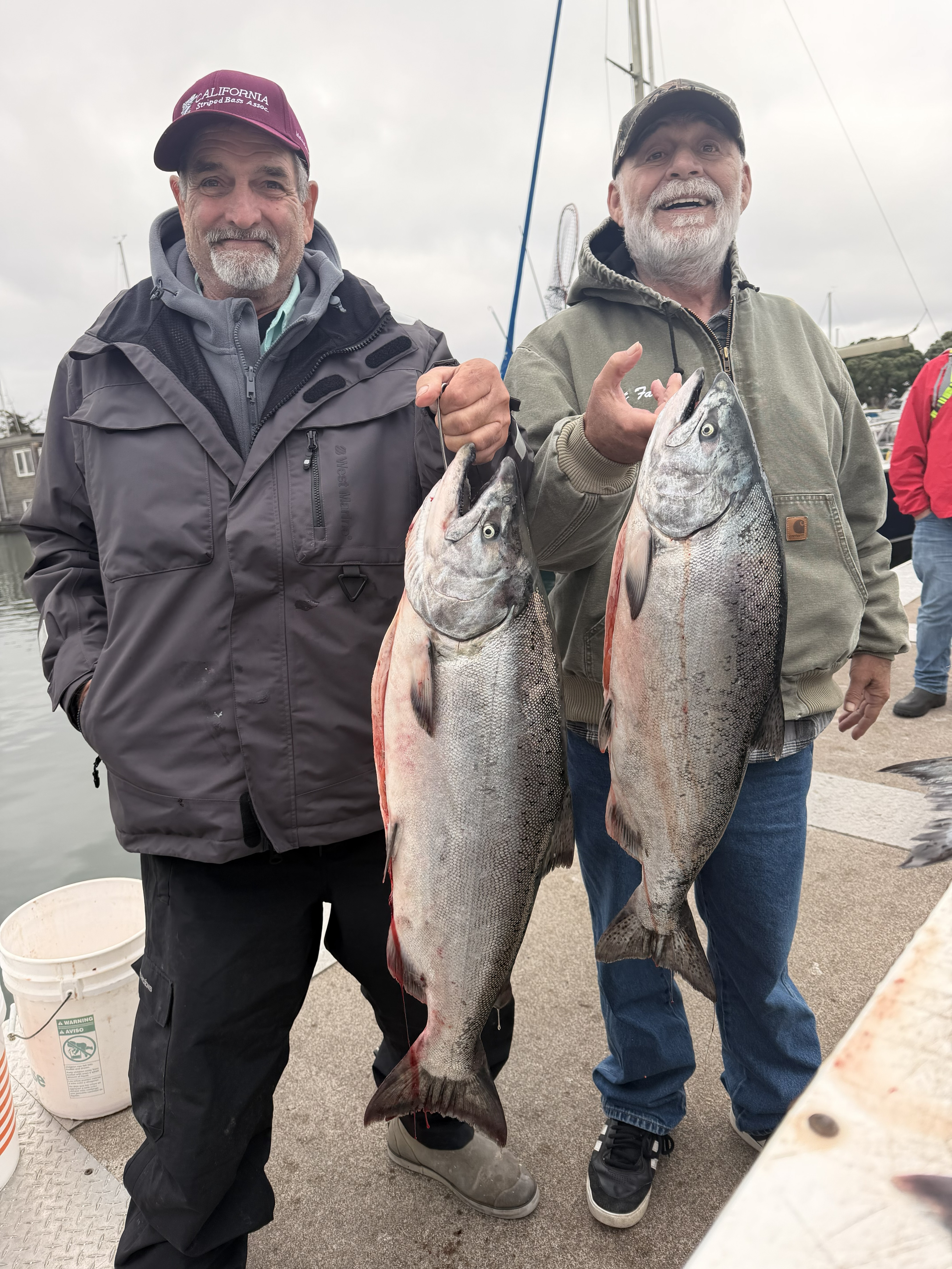 Two anglers holding king salmon on the dock