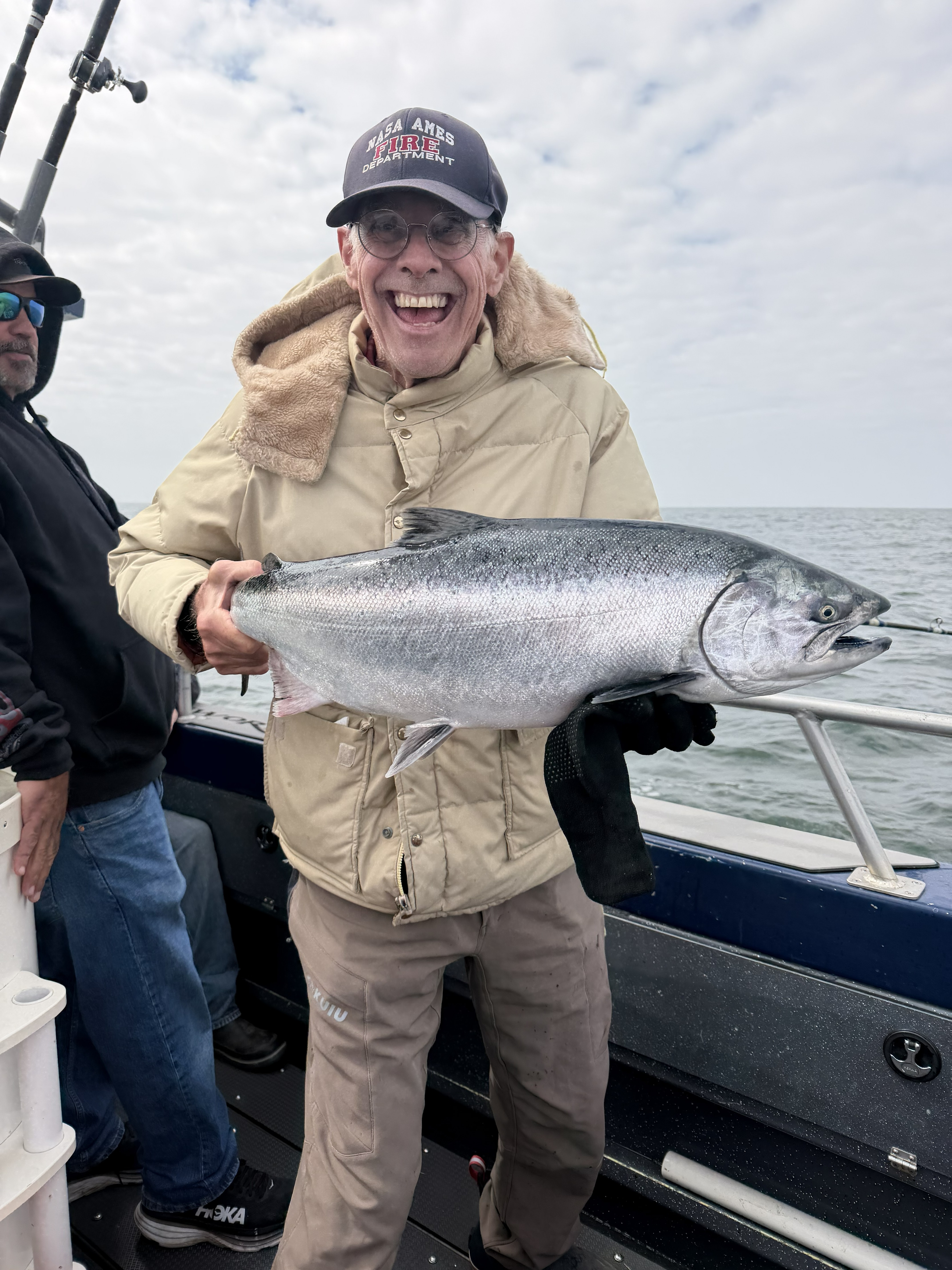 A laughing angler holding a king salmon on deck