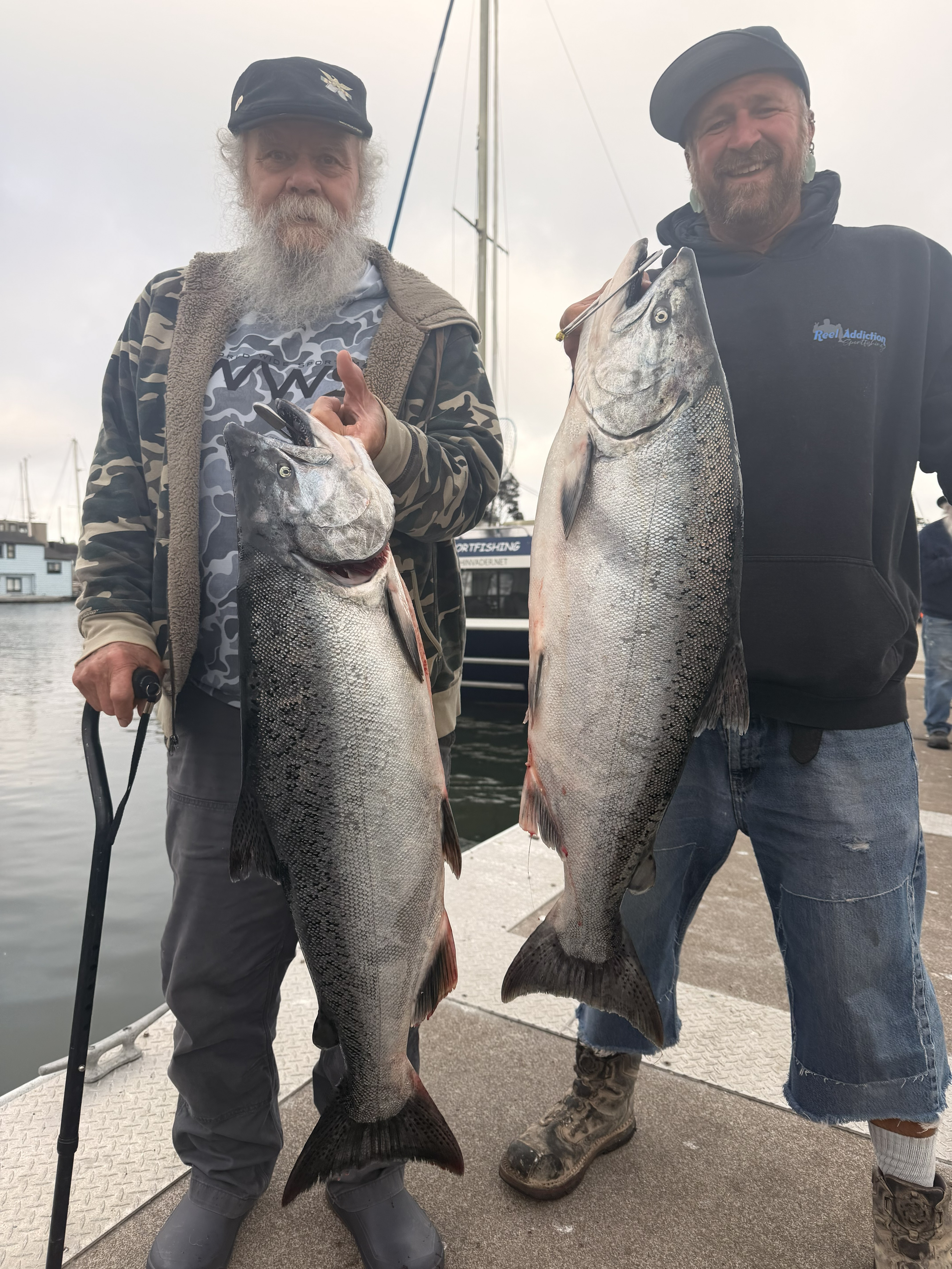 Two anglers on the dock holding king salmon