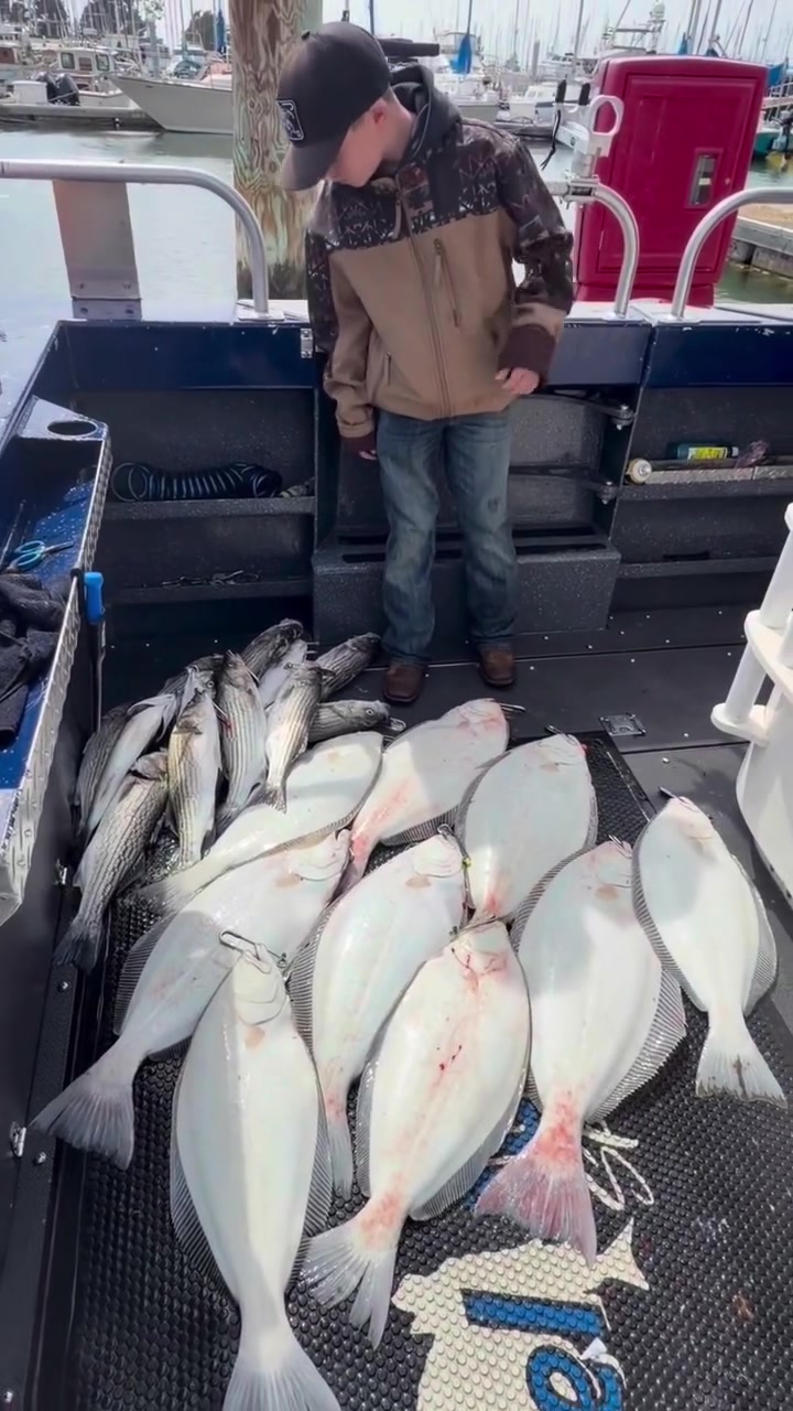 A young angler standing over a deck of halibut and salmon