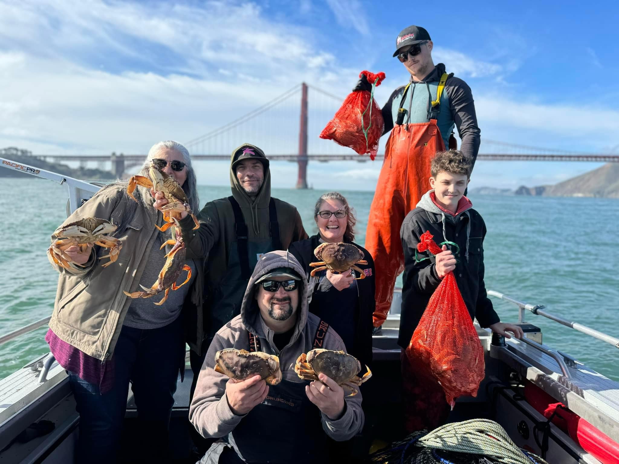 A family holding Dungeness crab on the boat with the Golden Gate behind them
