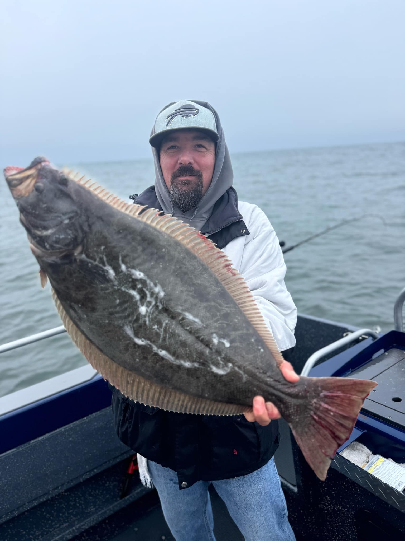 An angler holding a California halibut on a grey day