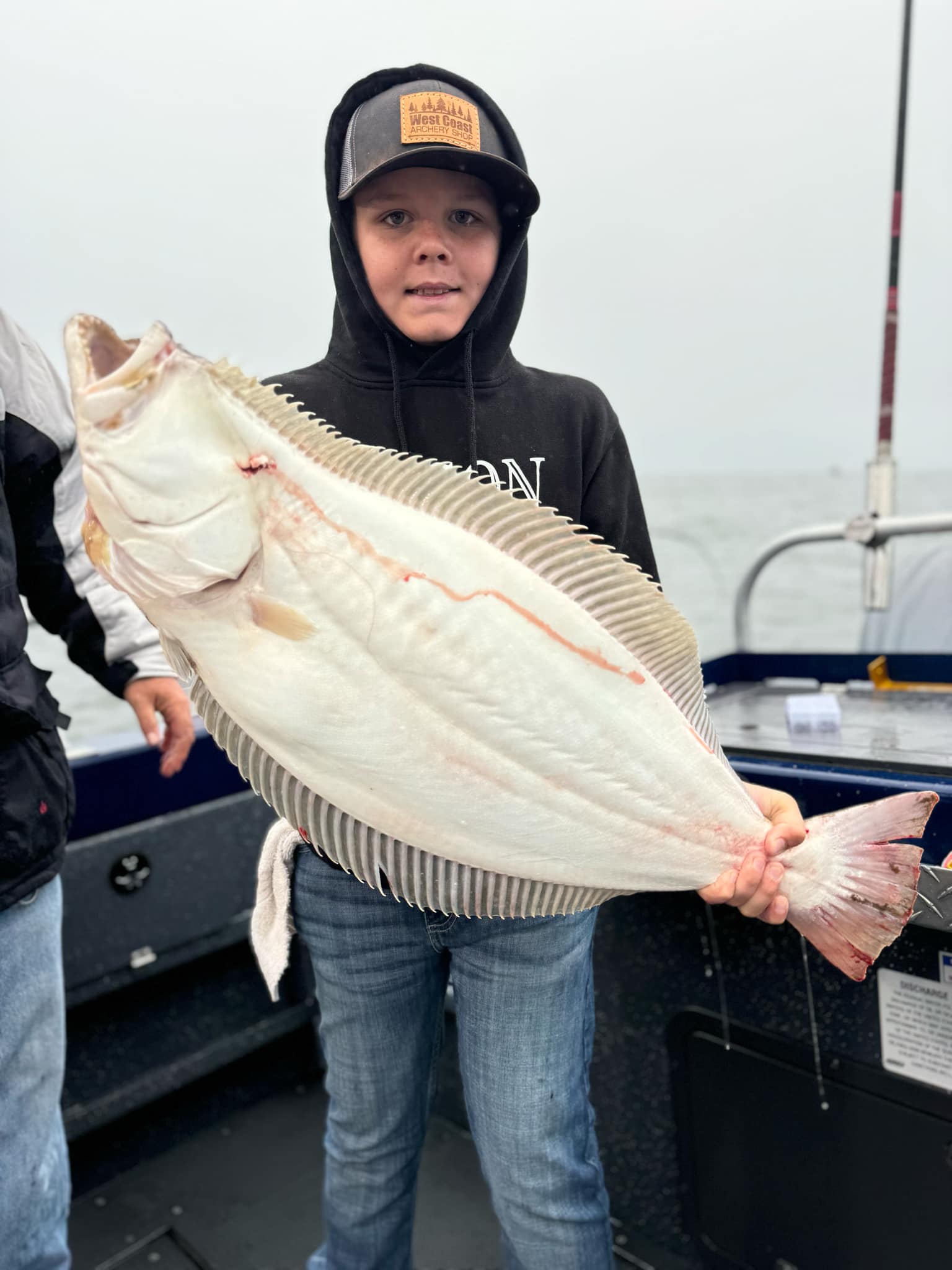 A young angler holding a large California halibut on deck