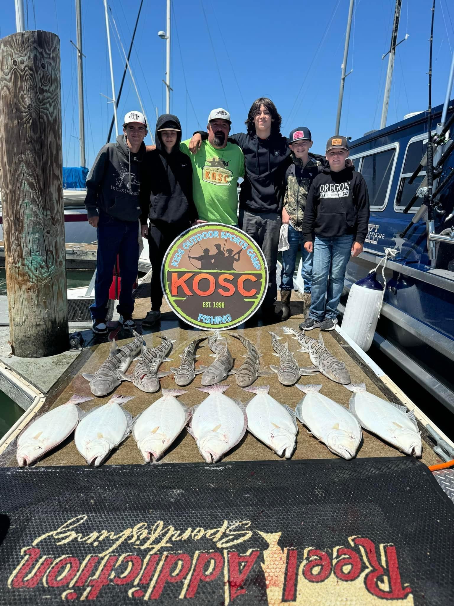 A youth group on the dock behind leopard sharks and halibut
