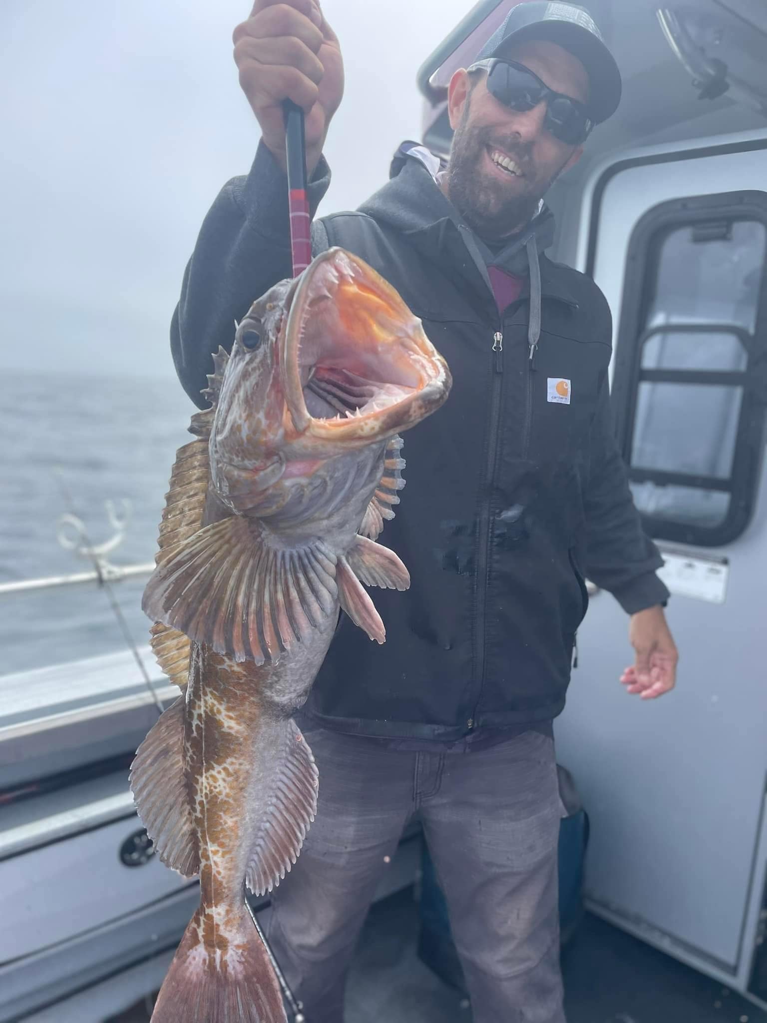 An angler holding up a lingcod