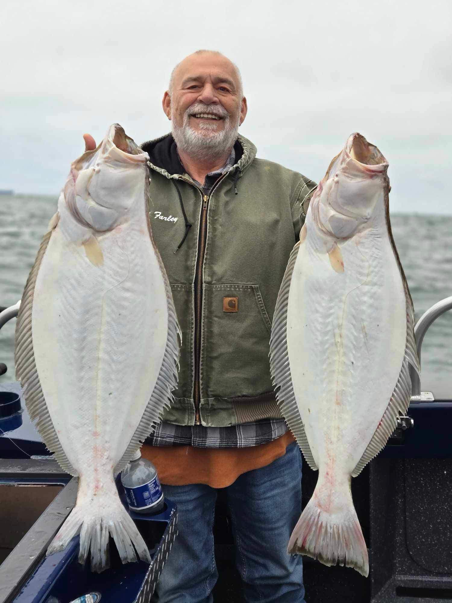 A smiling angler holding two big California halibut