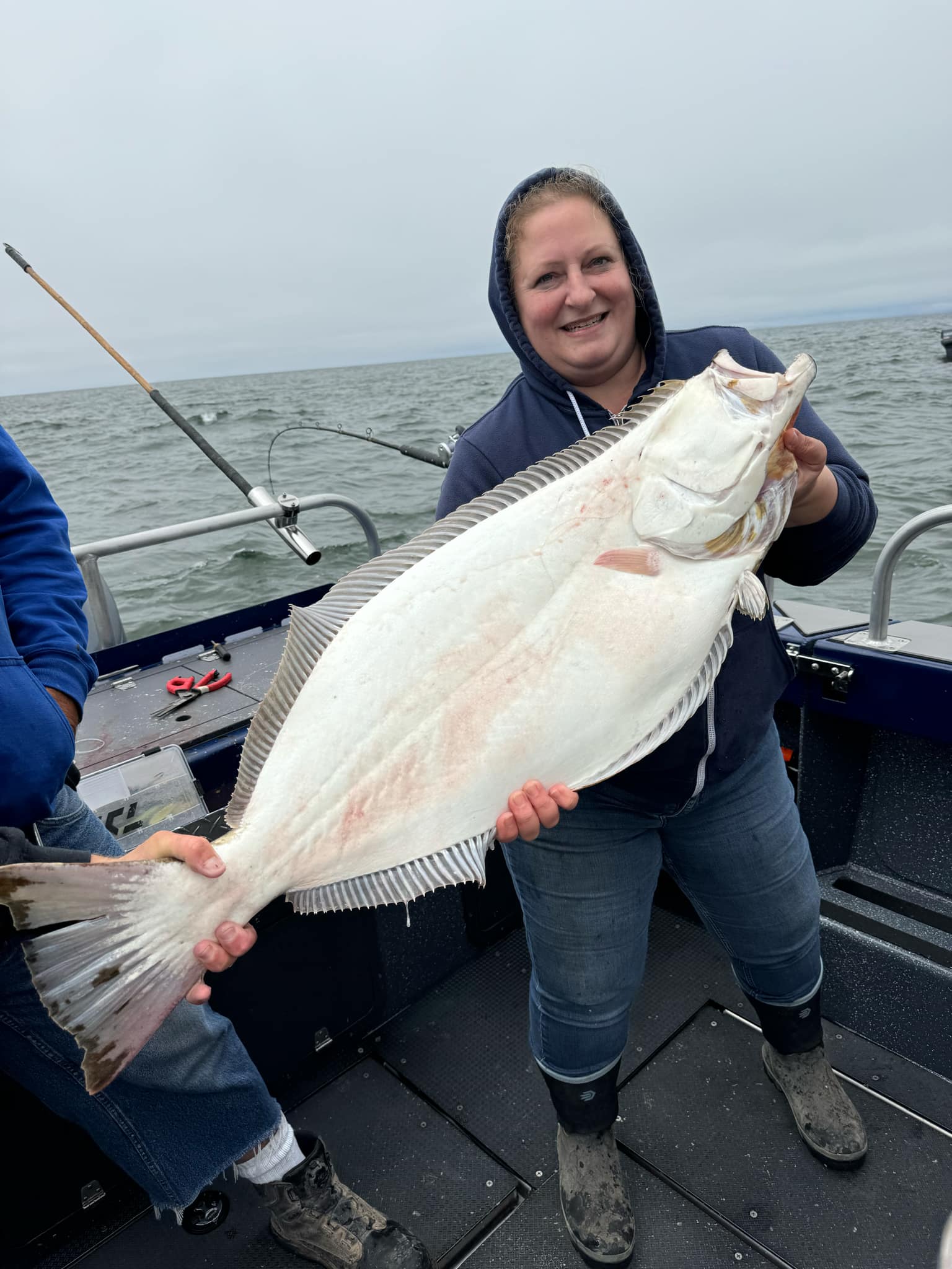 A woman holding a California halibut on deck