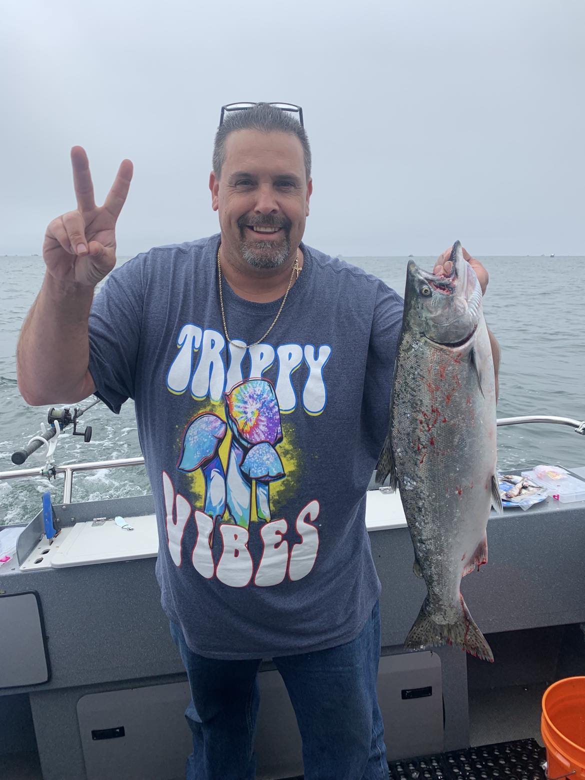 An angler giving a peace sign while holding a king salmon