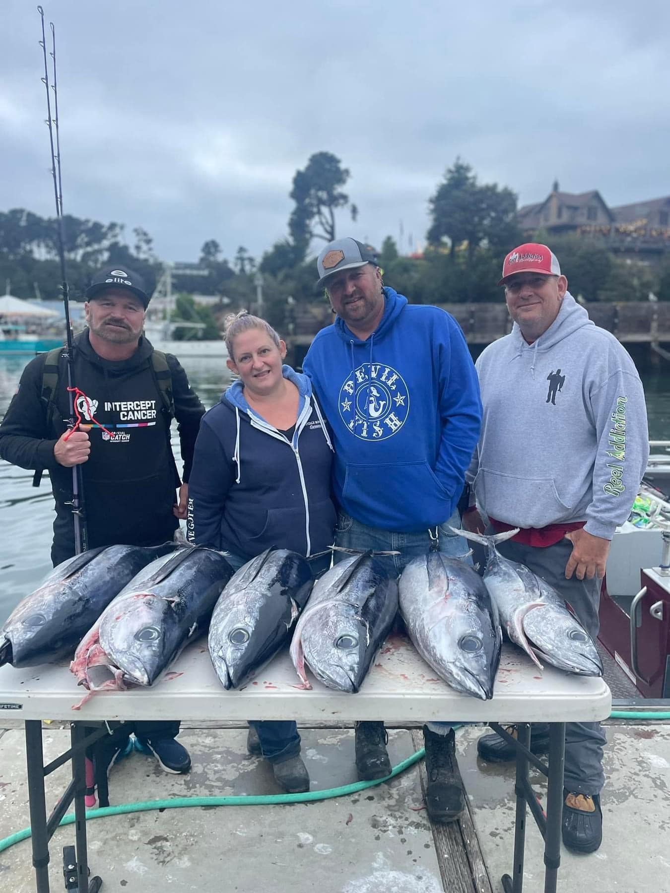 Four anglers on the dock behind a table of albacore tuna