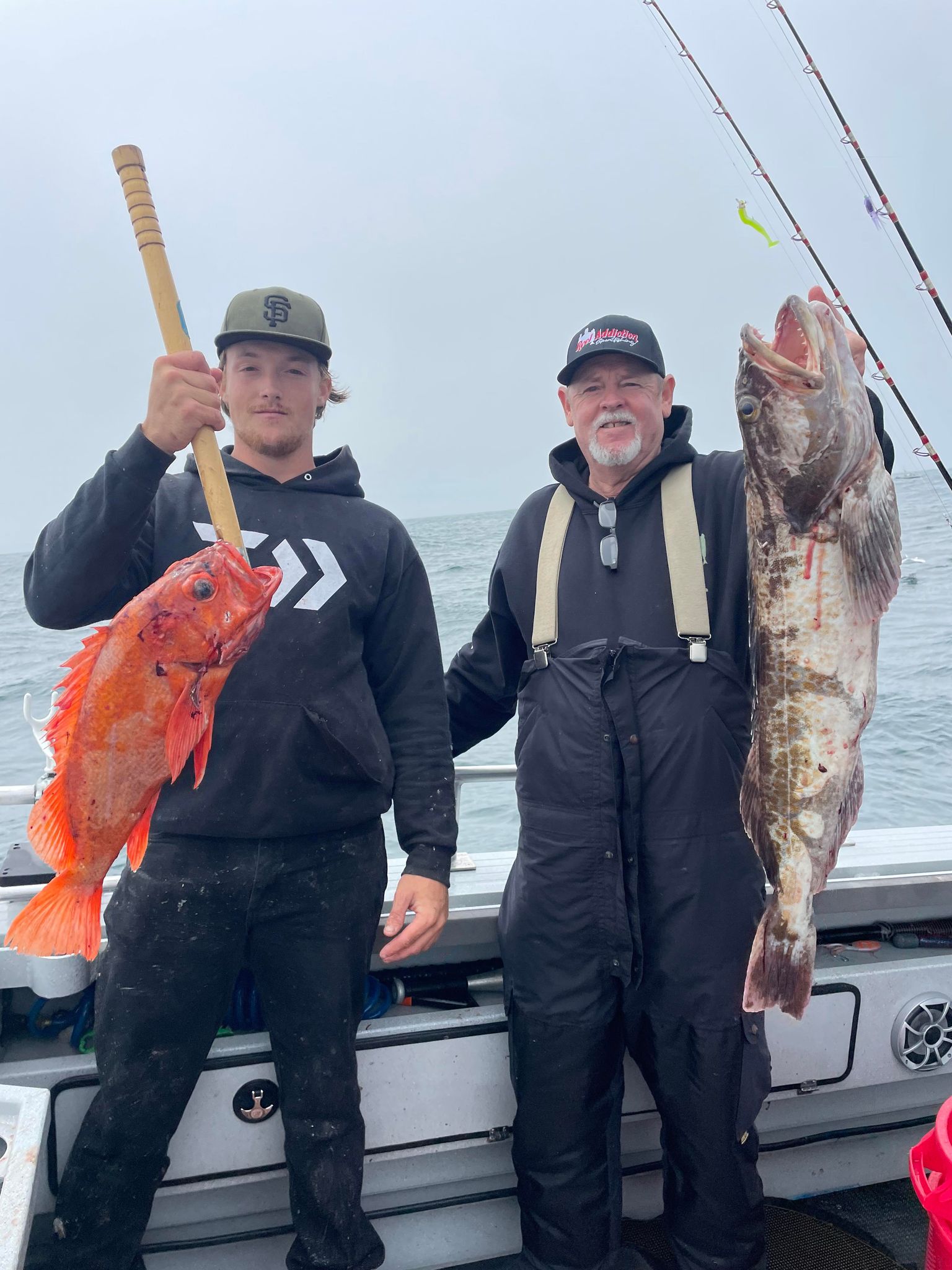 Two anglers holding a vermilion rockfish and a lingcod