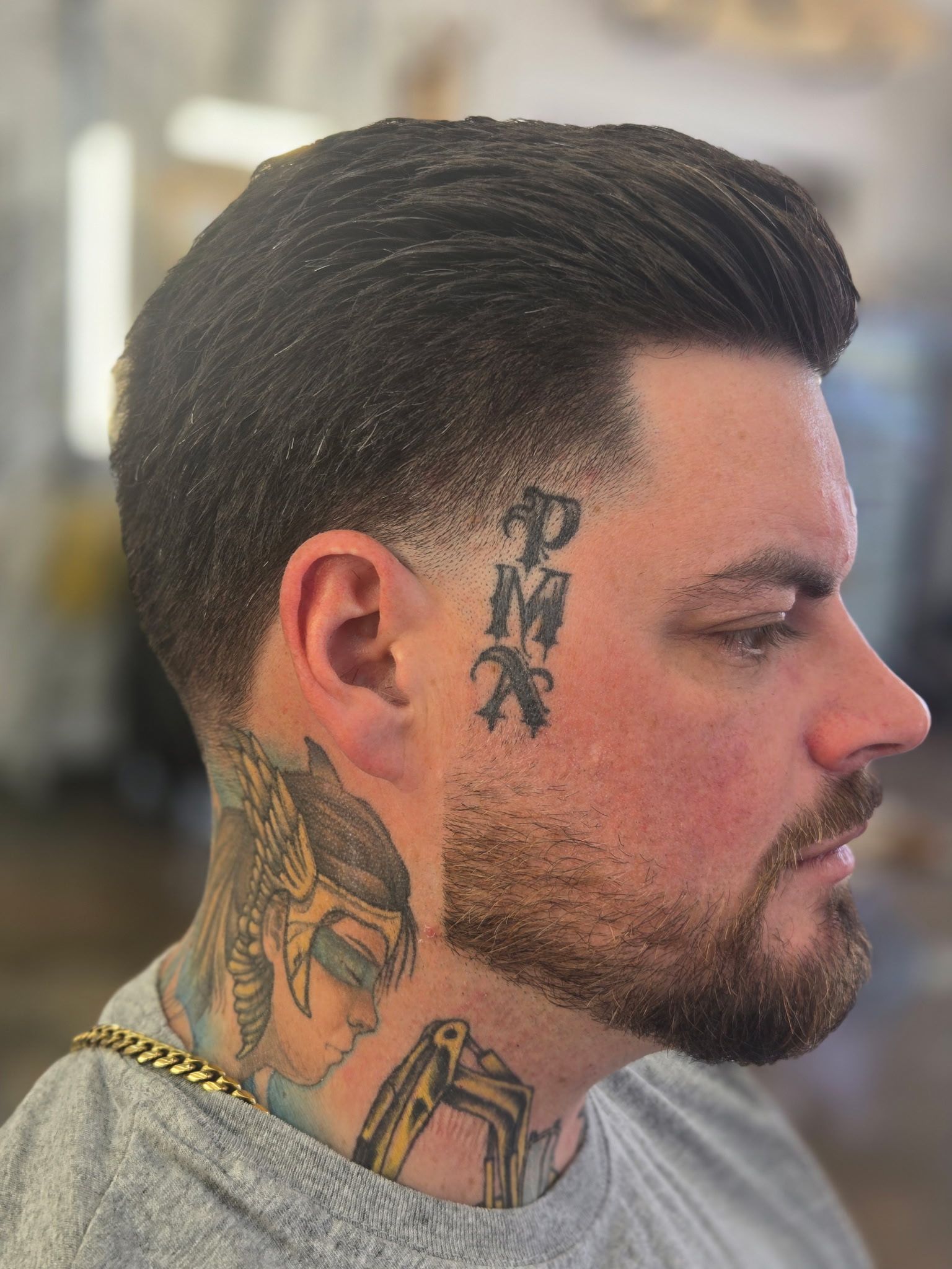 Man with fresh fade haircut and neck tattoos at a barbershop