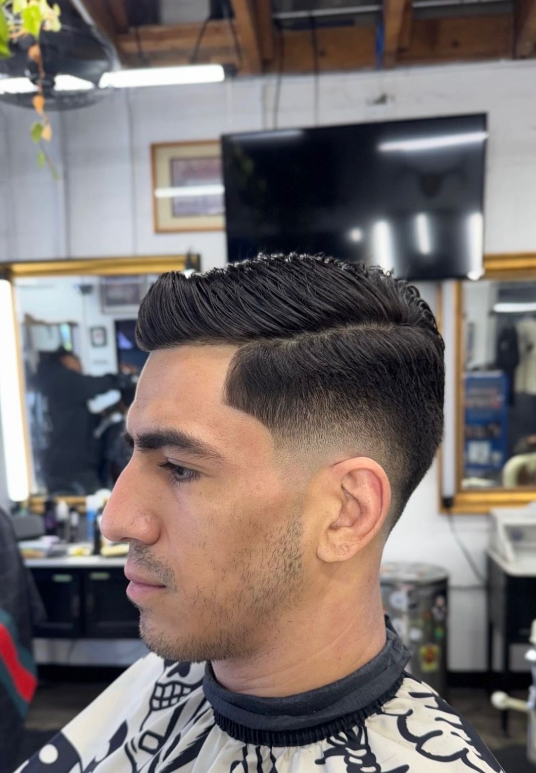 Man with fresh fade haircut sitting in barber chair at barbershop
